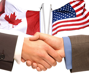Hands shaking, U.S. and Canadian flags